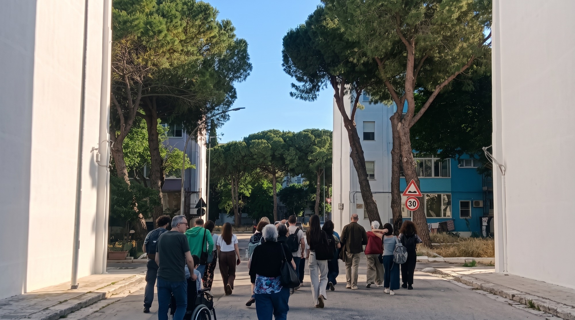 Una camminata di quartiere fra gli edifici, con abitanti di ogni età